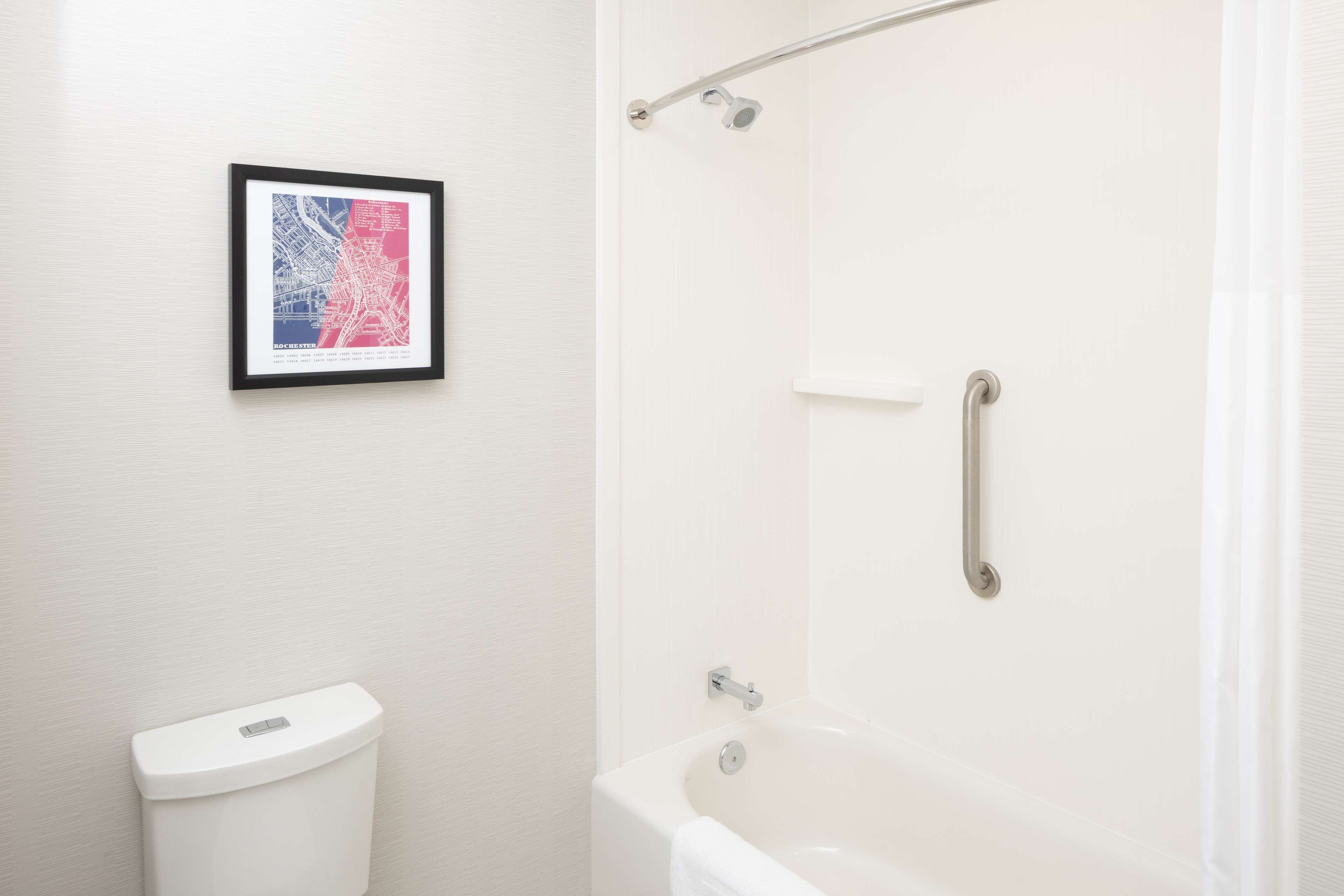 Ein Badezimmer mit Toilette, einer Badewanne mit Duschvorhang und einer gerahmten Karte an der Wand.