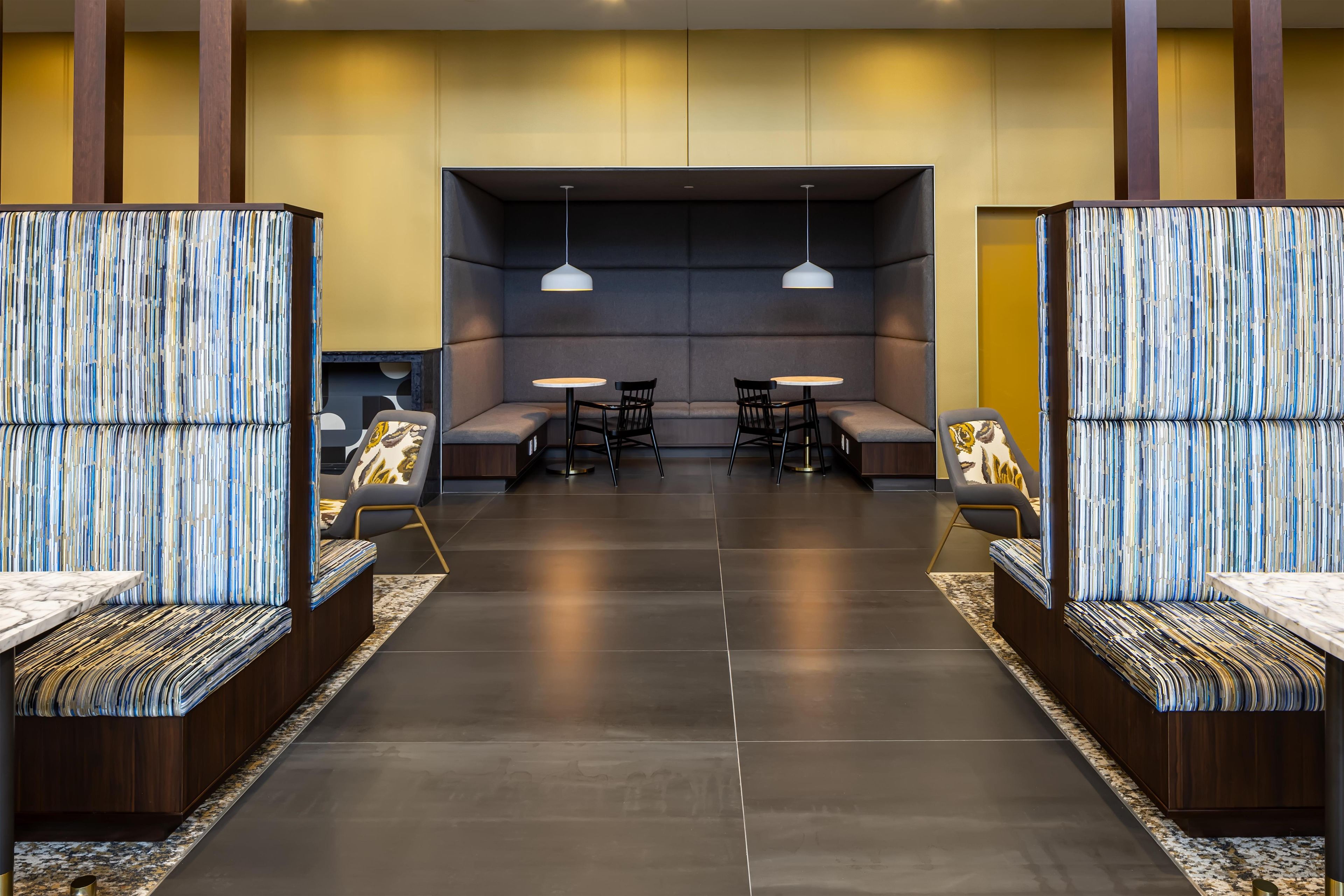 Een moderne hotellobby met een centraal zitgedeelte, twee tafels en een bank.