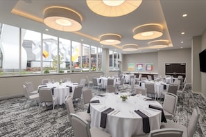 A conference room with round tables, white tablecloths, and grey chairs.