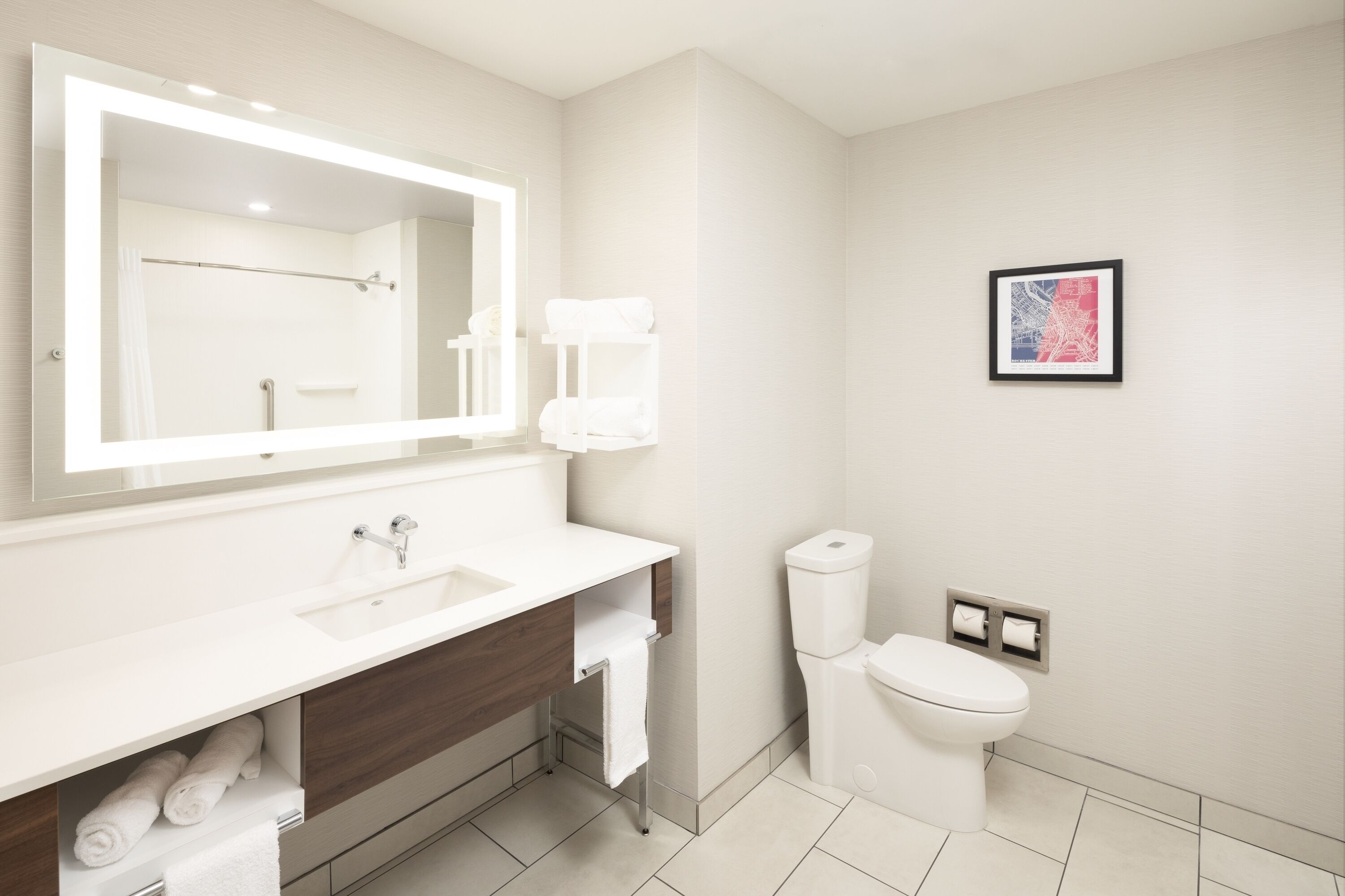 A modern bathroom with a large mirror, white sink, and toilet.