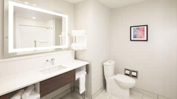 A modern bathroom with a large mirror, white sink, and toilet.