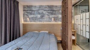 A modern hotel room with a large bed, wooden headboard, and a built-in wardrobe with sliding doors. - Le Carrousel, Premium 4 persons in Nantes Camping***** (Nantes)