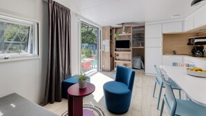 A modern kitchen with a dining area, a blue chair, and a small table with a plant. - Le Carrousel, Premium 4 persons in Nantes Camping***** (Nantes)