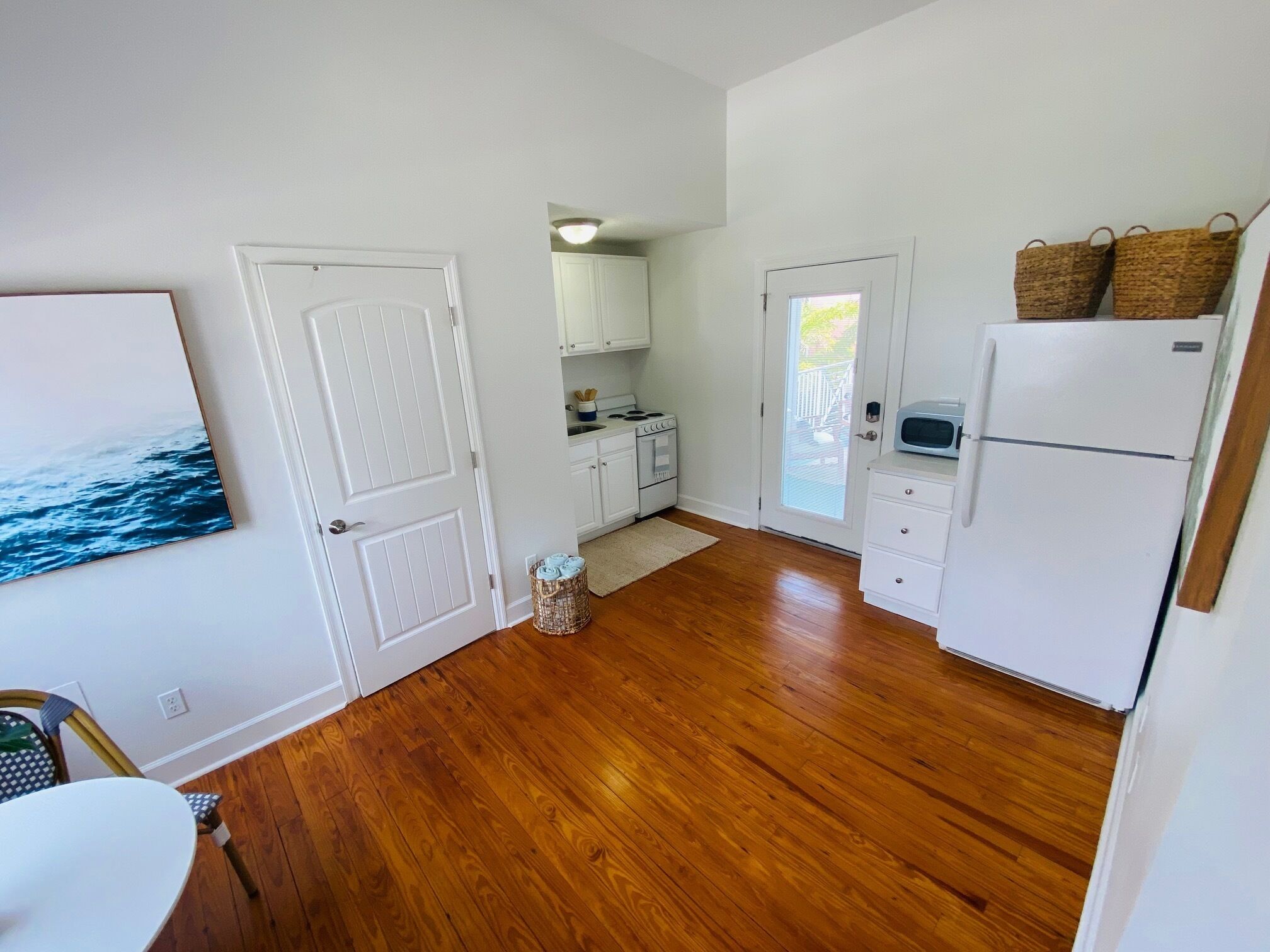 A compact kitchen with white cabinets, a refrigerator, and a microwave.