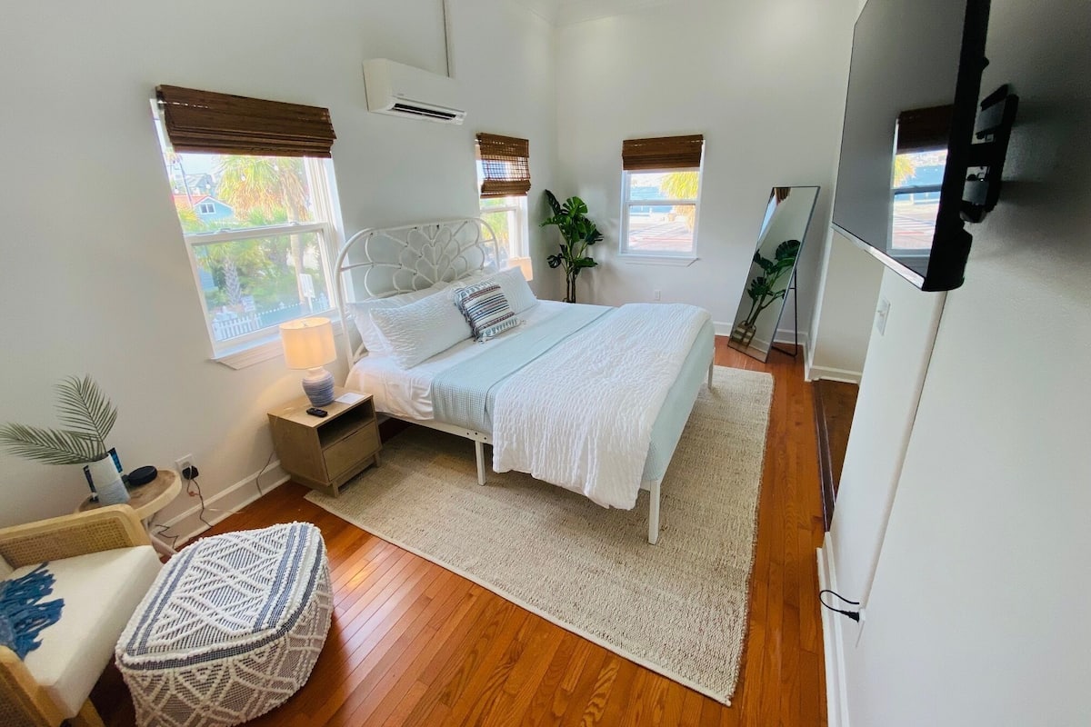 Un dormitorio con cama, mesitas de noche, un espejo y televisión.