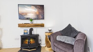 A cozy living room with a fireplace, a comfortable couch, and a wall-mounted TV.