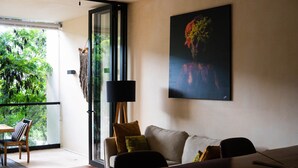 Un salon moderne avec un canapé, une table à manger et une grande fenêtre donnant sur un espace verdoyant.