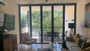 Un salon moderne doté d’un téléviseur à écran plat, d’un fauteuil en cuir, d’un canapé et d’un coin repas avec une table et des chaises.