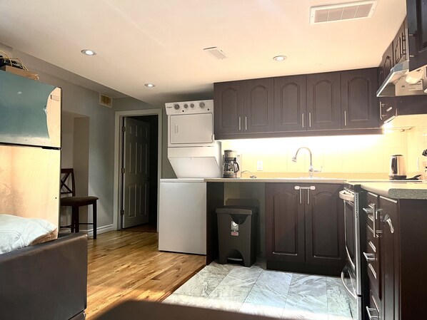 A compact kitchen with dark cabinets, a built-in oven, a refrigerator, and a coffee maker.