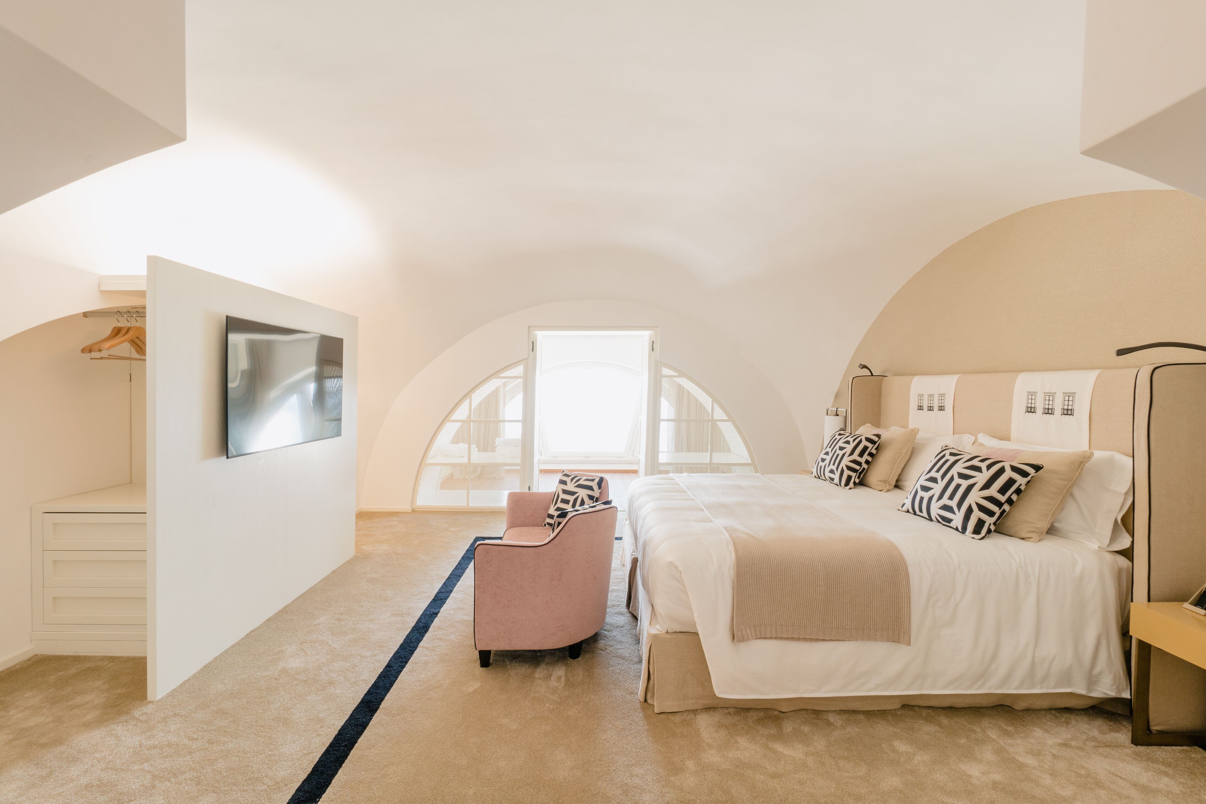 Une chambre à coucher avec un lit, une chaise, une télévision et une armoire.