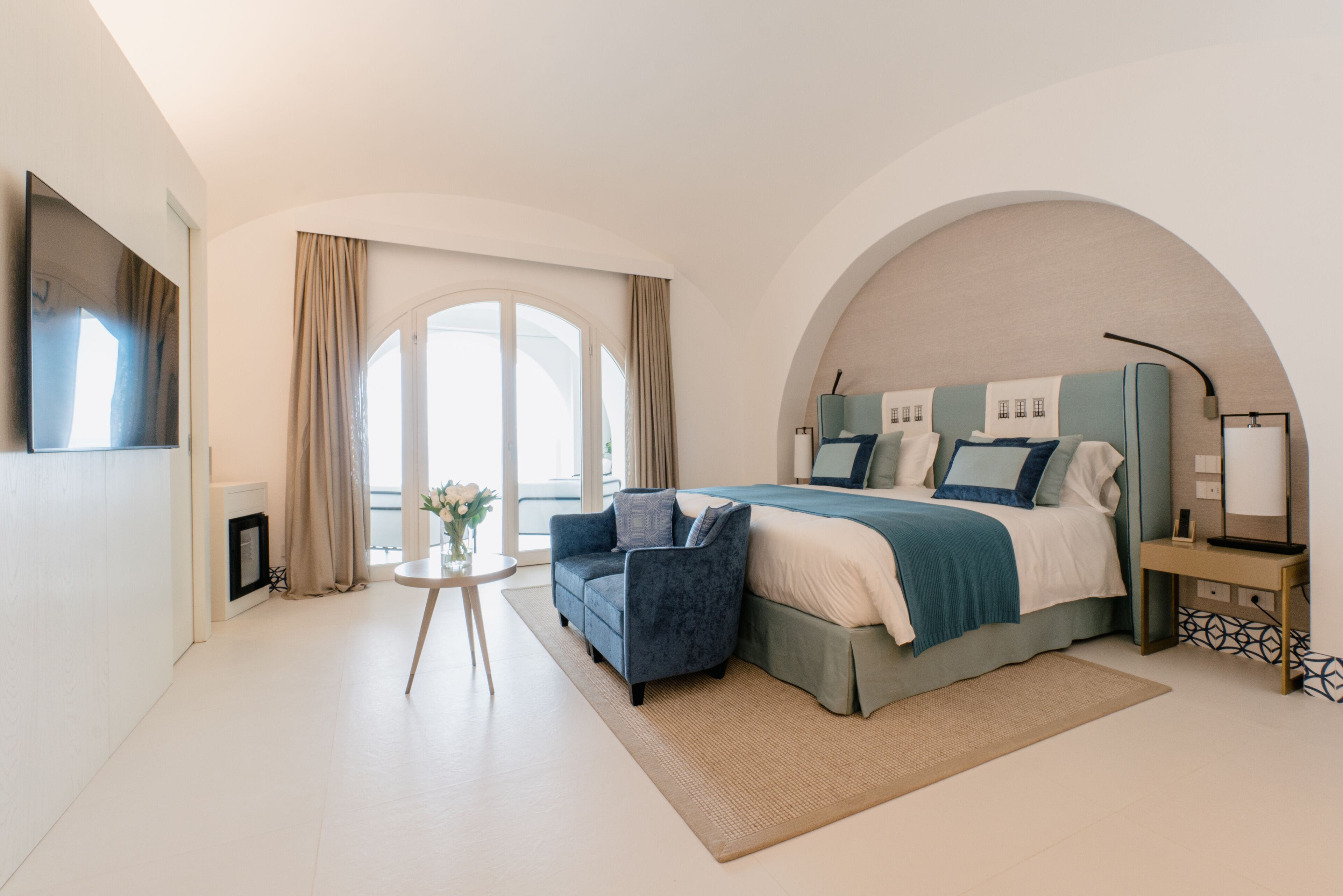 A modern bedroom with a large bed, a sofa, and a small table.
