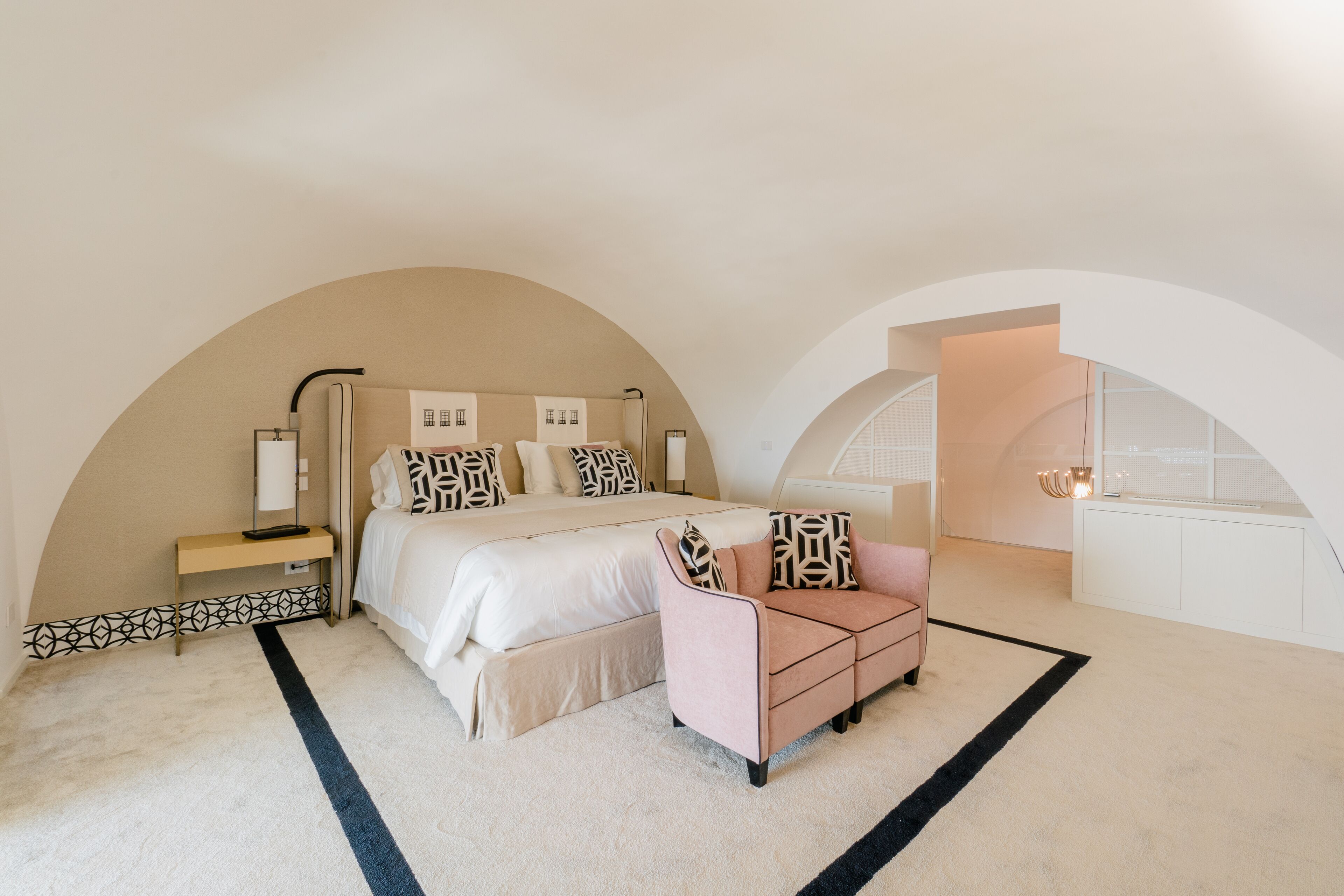 A bedroom with a large bed, a bedside table, a chair, and a walk-in closet.