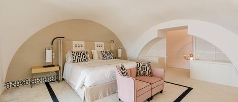 A bedroom with a large bed, a bedside table, a chair, and a walk-in closet.