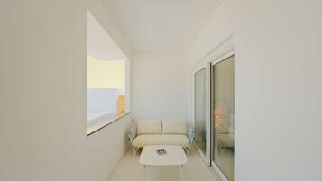 A minimalist room with a white sofa, a small white table, and a large window.