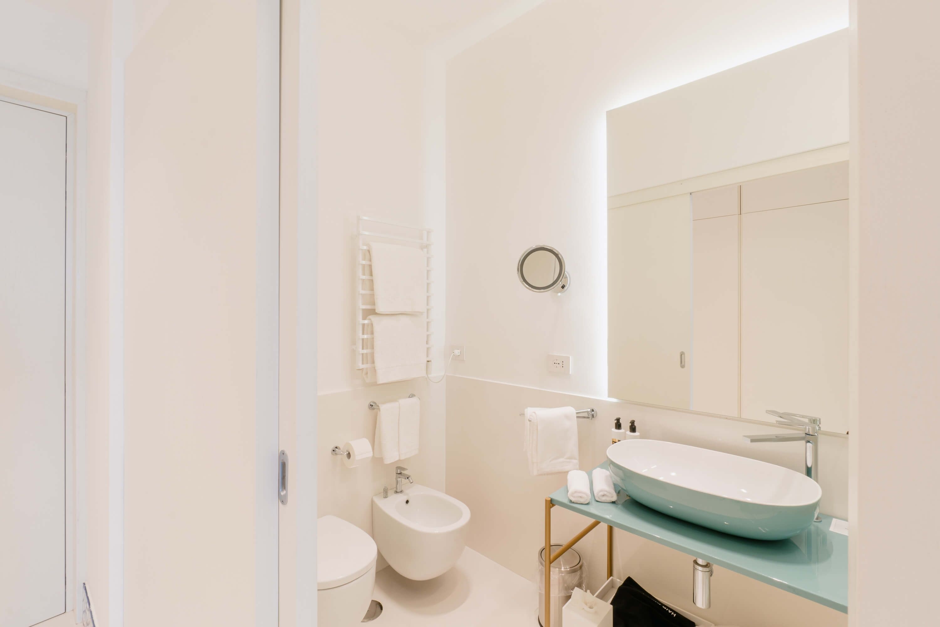A modern bathroom with a bidet, a sink with a mirror, and a towel rack.