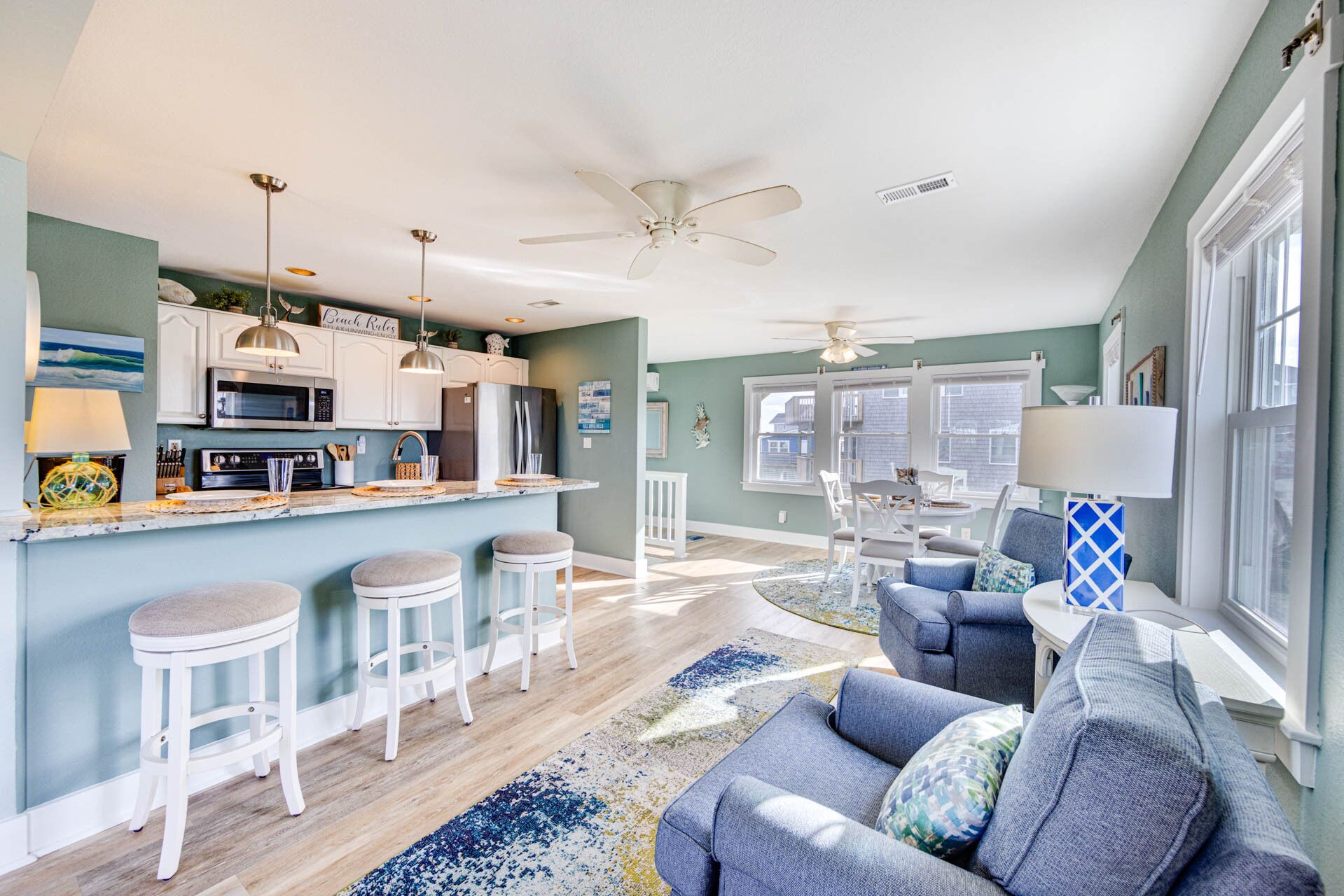 A spacious living room with a grey sofa, a coffee table, and a dining area with bar stools.