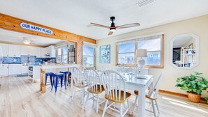 Une cuisine spacieuse avec des meubles blancs, un plafond en bois et une vue sur l’extérieur.