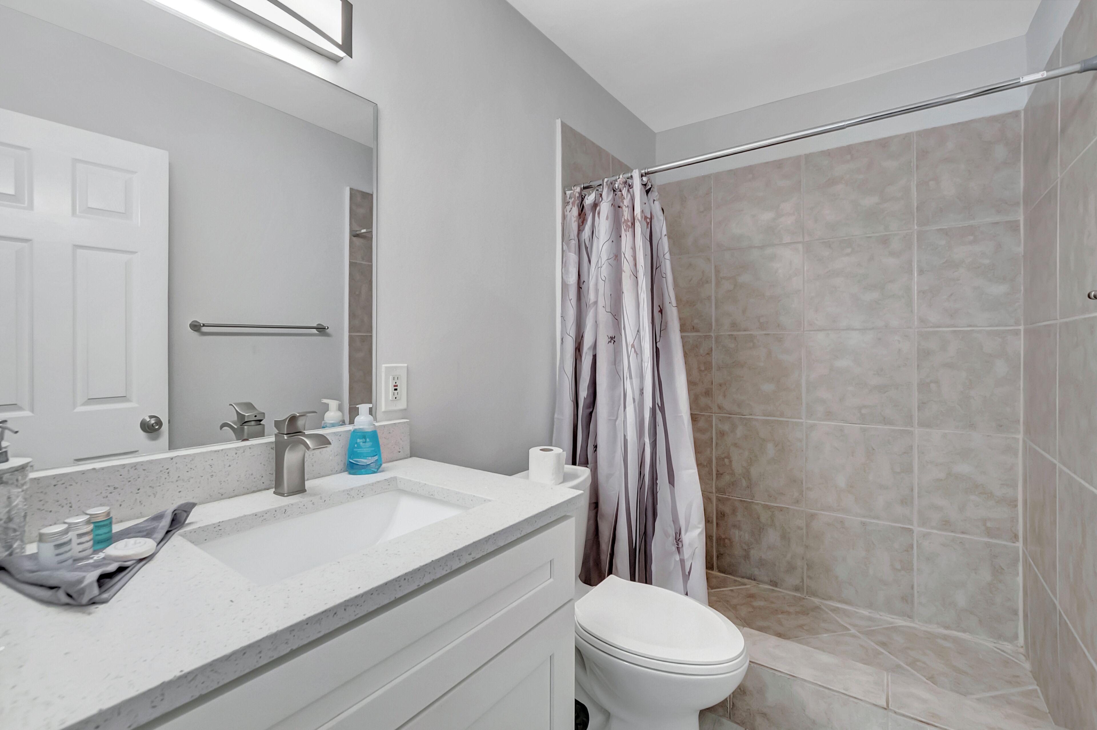 Un baño con lavamanos, espejo y retrete blancos.