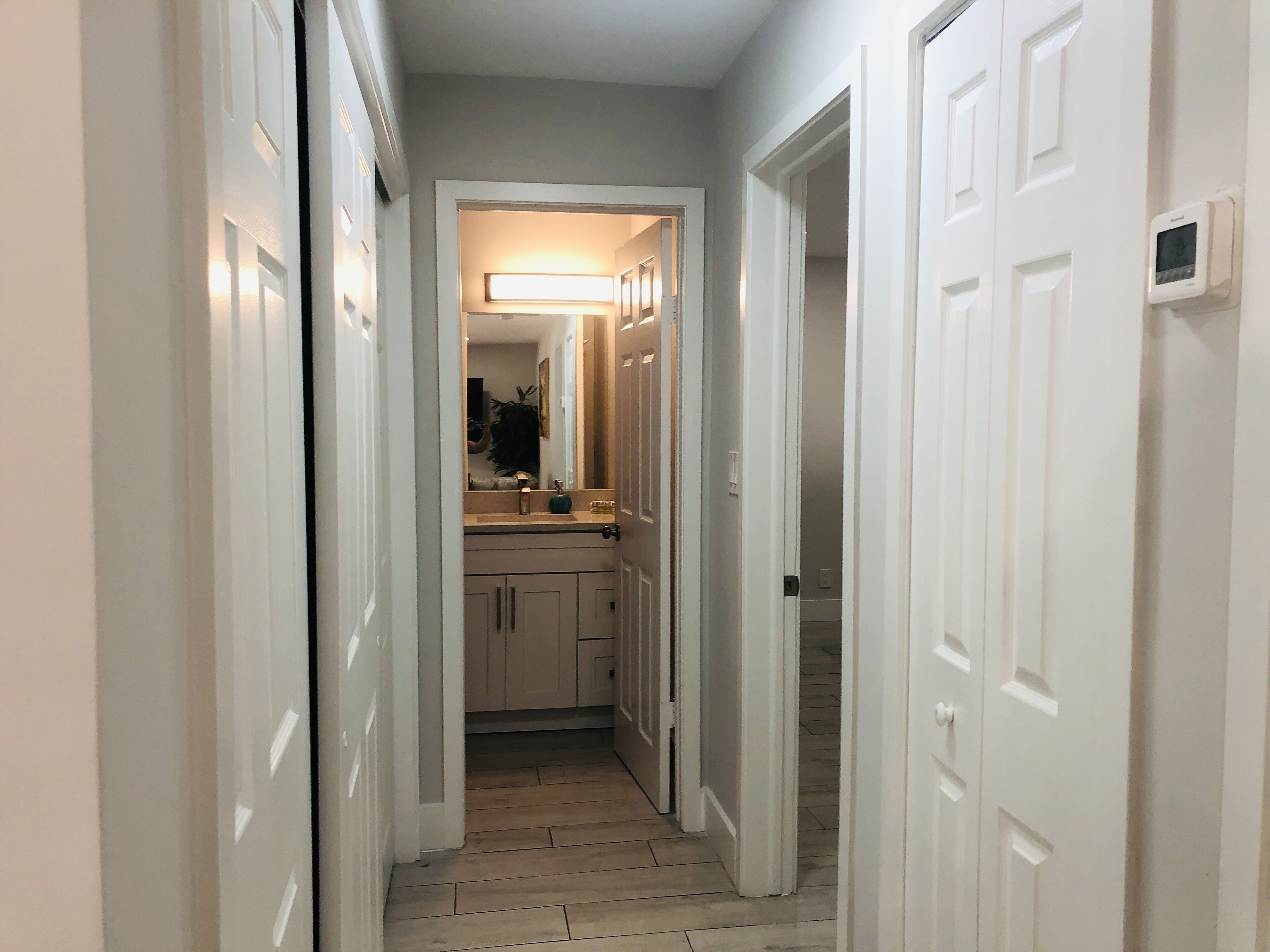 A narrow hallway with white doors and a wooden floor.