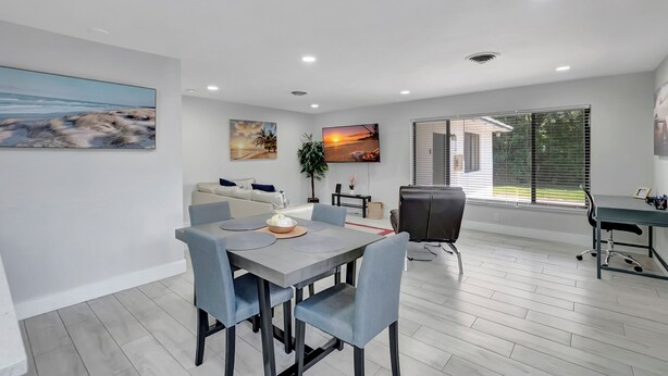 Una sala de estar moderna con comedor, un sofá, una mesa de centro y un televisor montado en la pared.