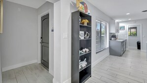 Una cocina moderna con una isla integrada, muebles blancos y un ventanal con persianas.