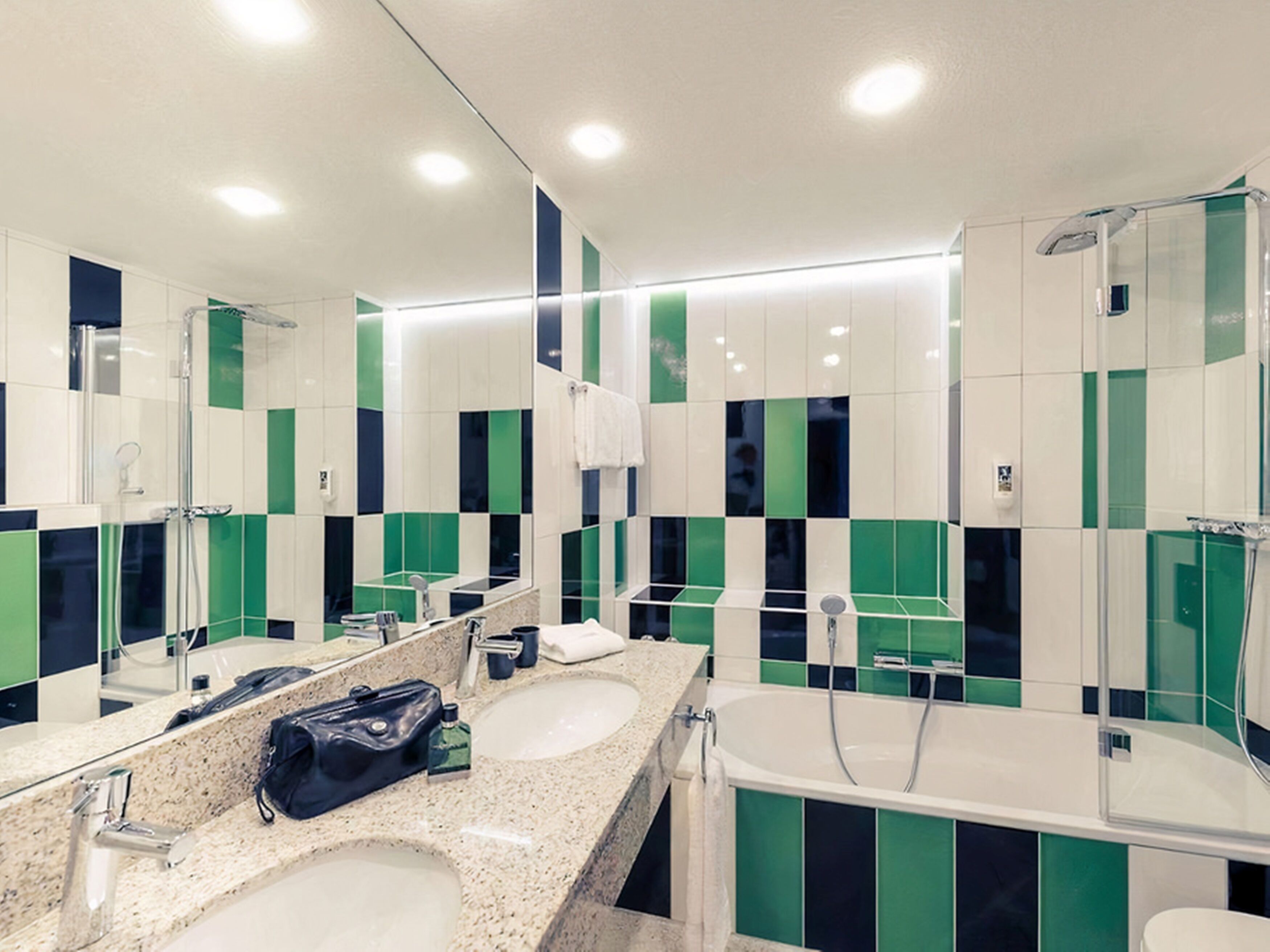 A modern bathroom with two sinks, a large mirror, and a shower area.
