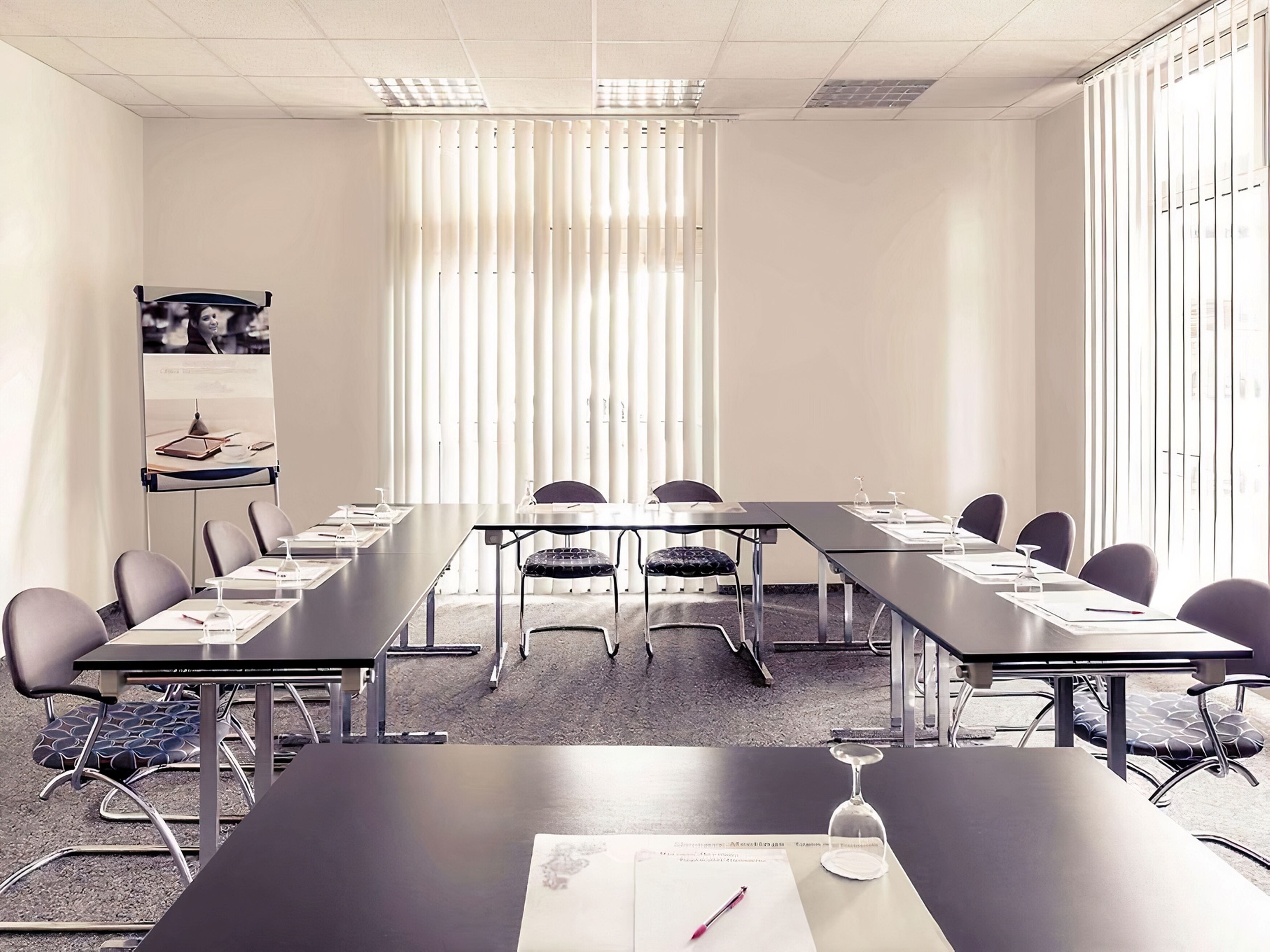 A conference room with a long table, chairs, a podium, and a poster on the wall.