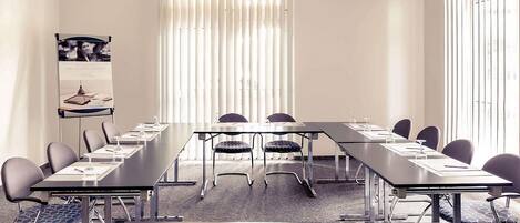 A conference room with a long table, chairs, a podium, and a poster on the wall.