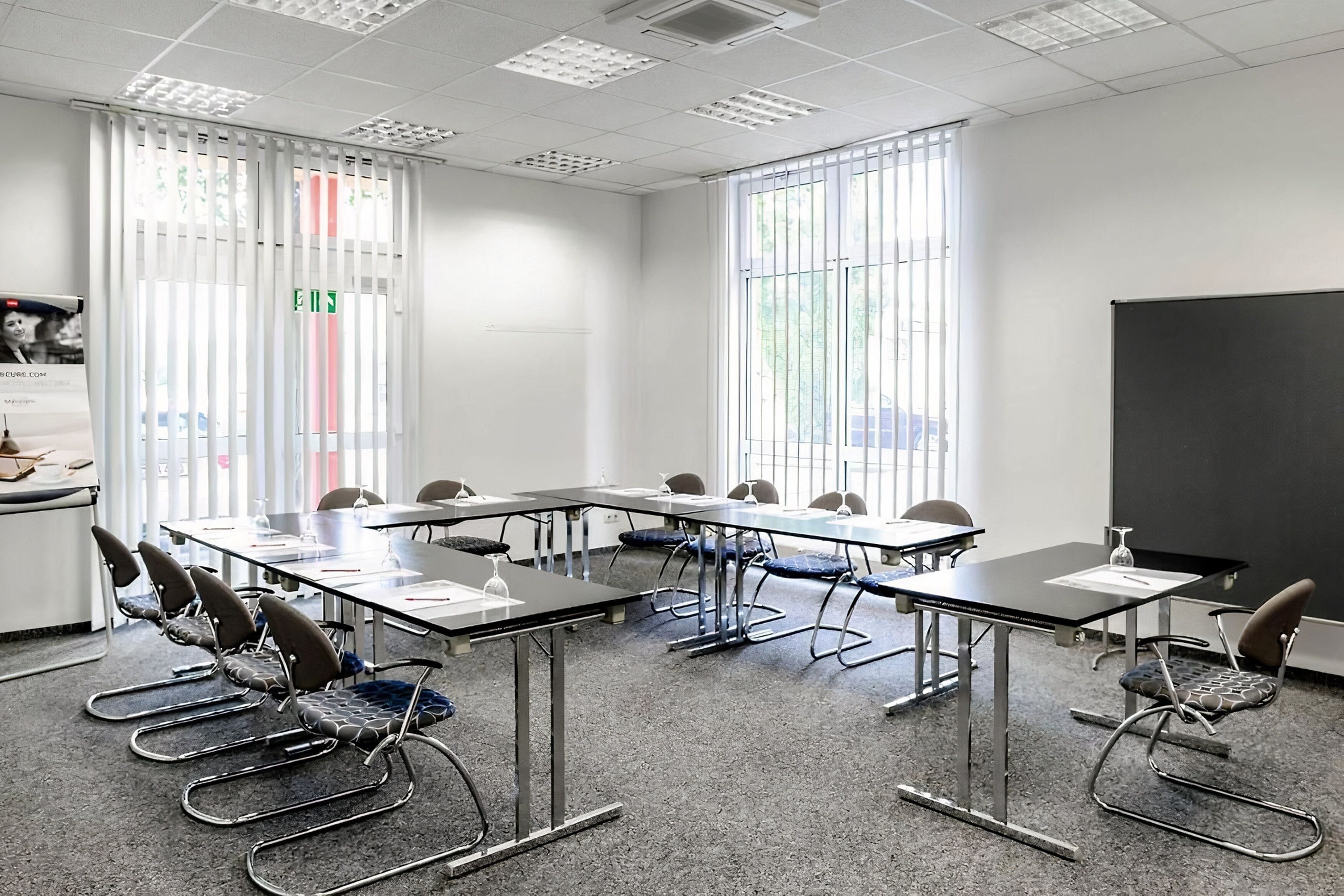 A conference room with tables, chairs, and a projector screen.
