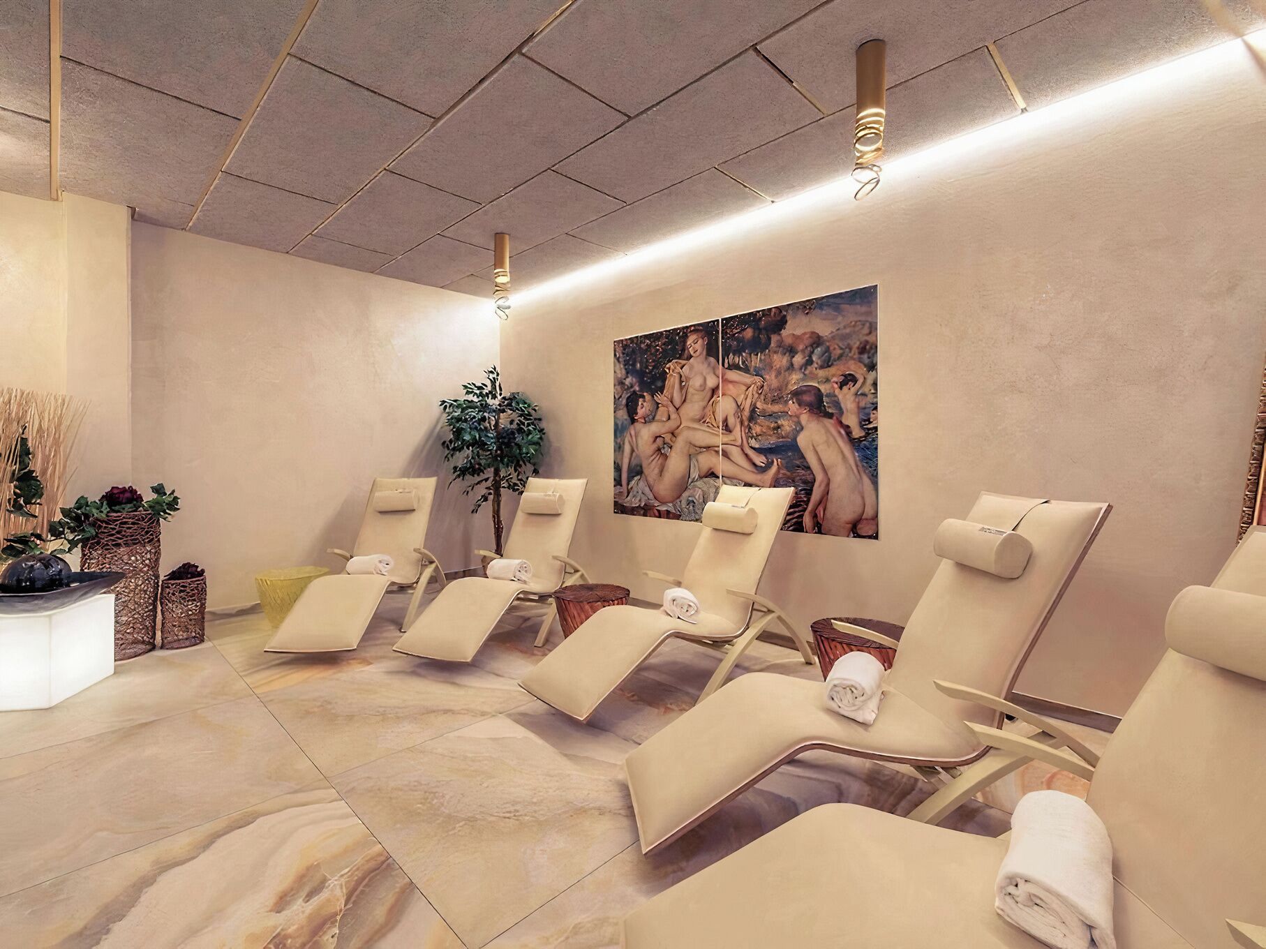 Ein Wellnessraum mit Liegesesseln, einer Massageliege und einem großen Gemälde an der Wand.