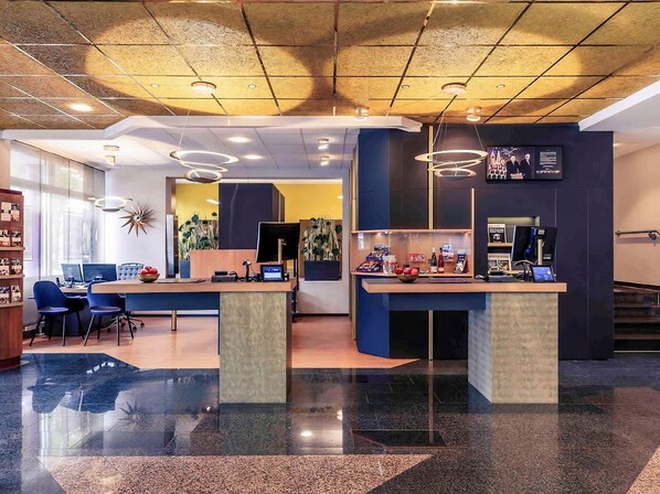 A modern reception area with a glass partition, a reception desk, and a seating area with chairs. - PLAZA INN Regensburg (Regensburg)