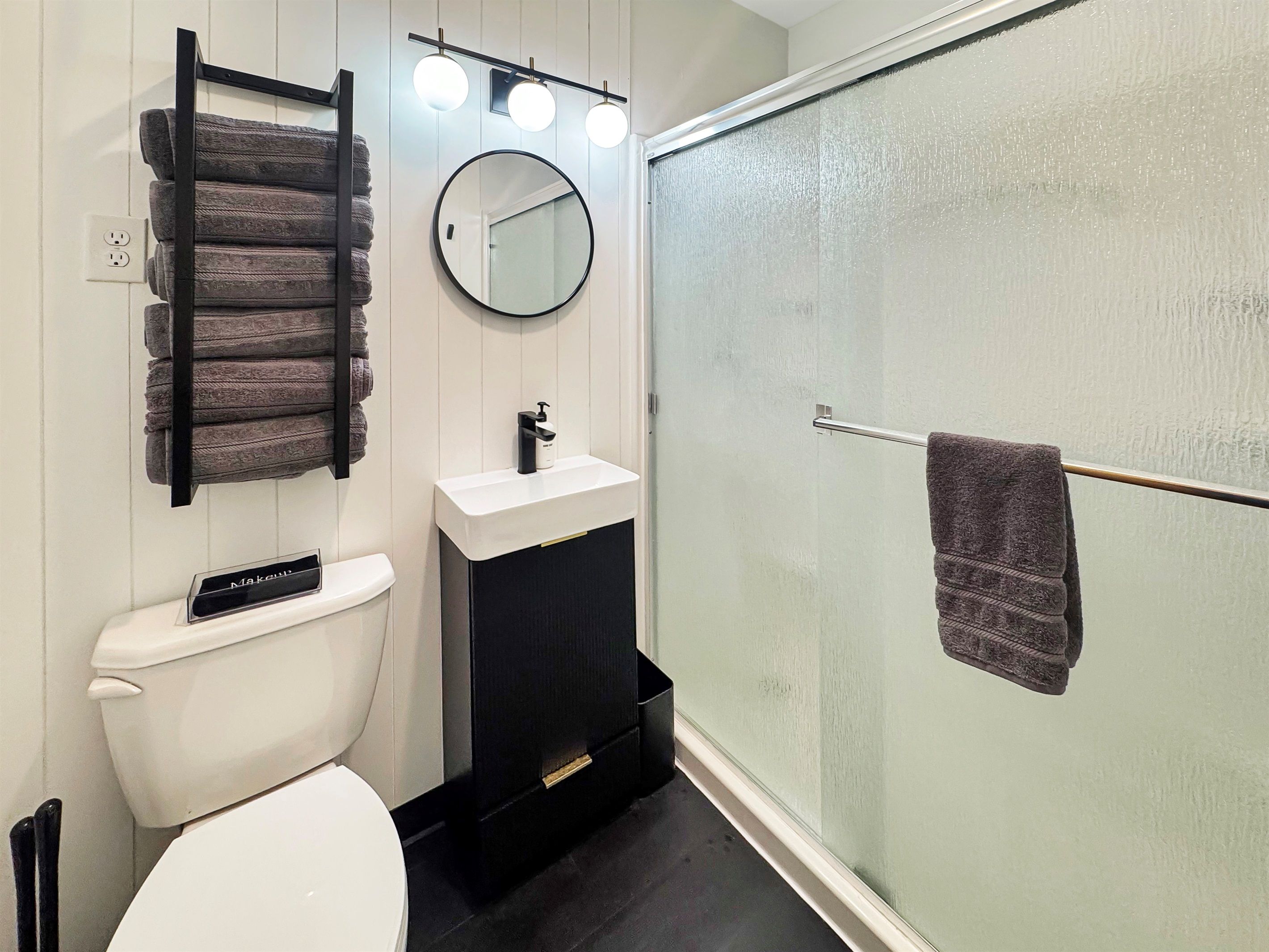 Een moderne badkamer met toilet, wastafel en een douchecabine van glas.