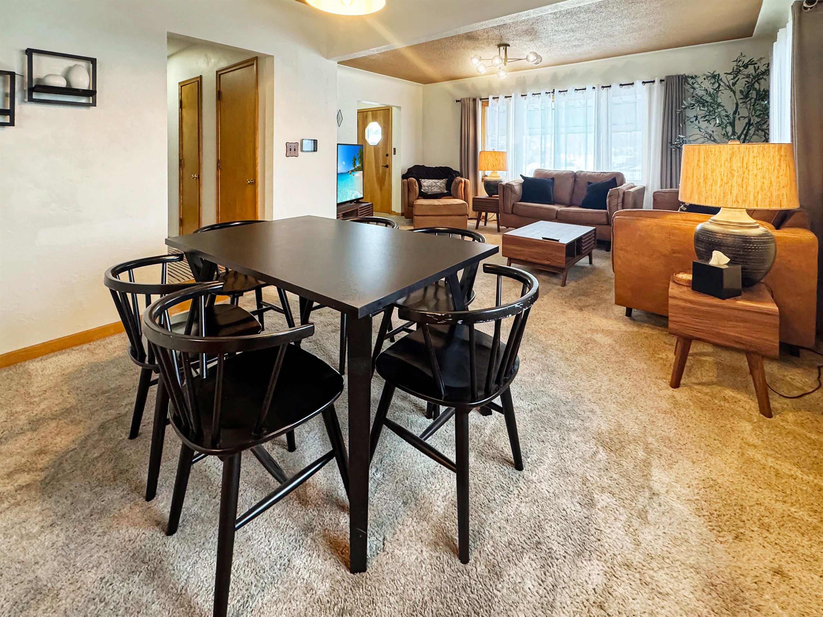 A living room with a dining table, chairs, a sofa, and a lamp.