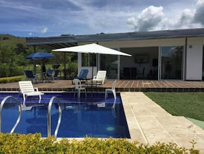 Ett modernt hus med en swimmingpool, utemöbler och en uteplats.