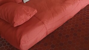 Un sofá rojo con dos cojines blancos y una almohada a juego.