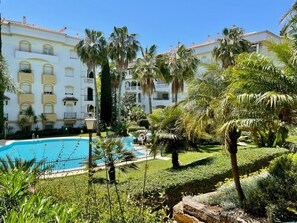 A hotel with a swimming pool surrounded by lush greenery and palm trees. - Hacienda de Nagüeles   EaW Homes (Marbella)