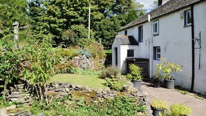 A white building with a stone wall and potted plants in front. - 3 bedroom accommodation in Sunderland, near Bassenthwaite (Sunderland, near Bassenthwaite)