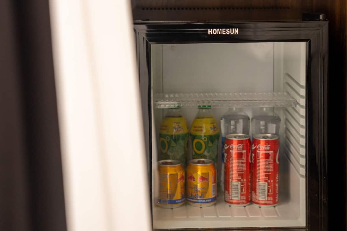 A glass-fronted refrigerator with a brand label, containing various beverages.