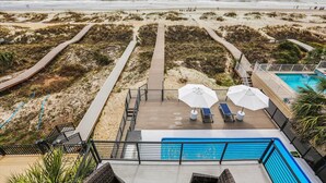 A pool area with two umbrellas, a wooden deck, and a view of the beach. - 7 Singleton Beach, Oceanfront, Private Pool (Hilton Head Island)