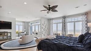 A modern bedroom with a large bed, a ceiling fan, and a view of the beach. - 7 Singleton Beach, Oceanfront, Private Pool (Hilton Head Island)