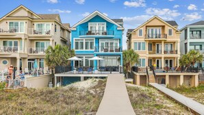 A beachfront property with a wooden walkway leading to a pool area, featuring multiple balconies and outdoor seating. - 7 Singleton Beach, Oceanfront, Private Pool (Hilton Head Island)