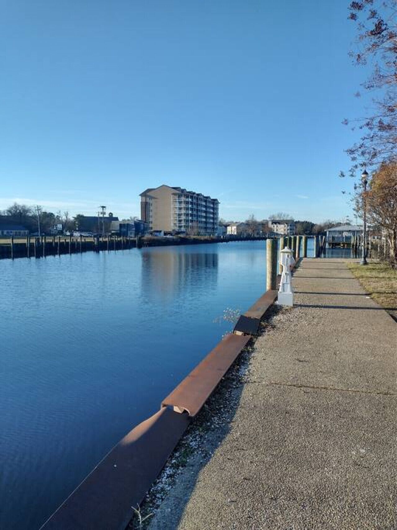 A waterfront hotel with a dock, a pedestrian path, and a clear view of the water.