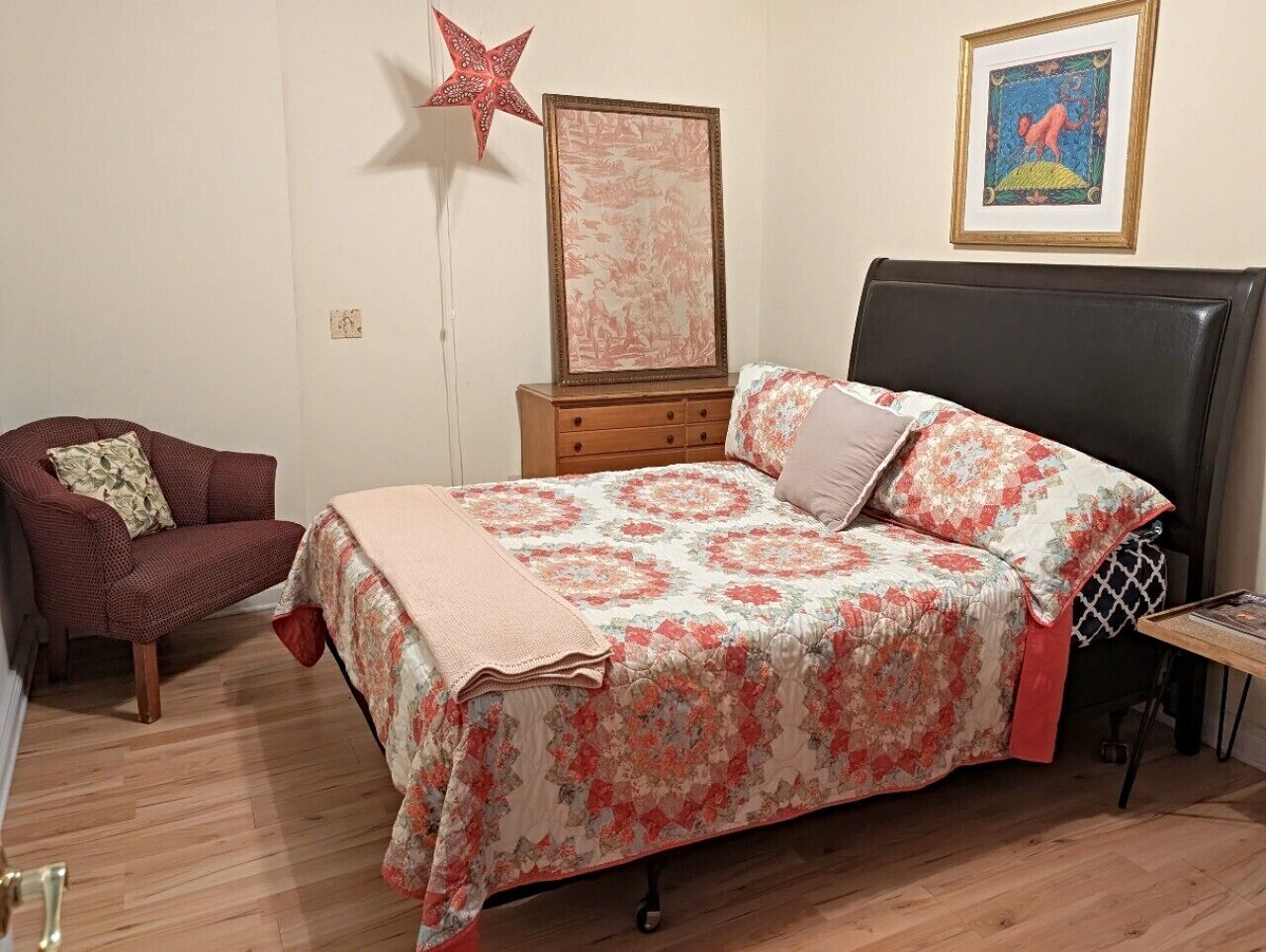Un dormitorio con cama, una silla, cómoda y decoración con estrellas, además de un cuadro en la pared.