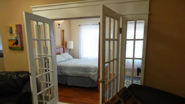 An open door leading to a bedroom with a bed, a nightstand, and a lamp.