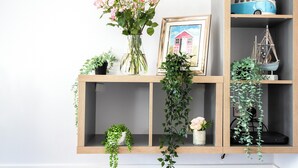 A wooden shelf with a vase of pink flowers, a framed picture of a pink house, and a model ship. - 3 bedroom accommodation in Sheringham (Sheringham)