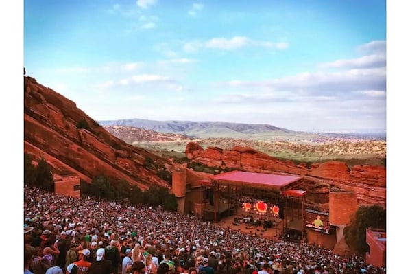 A large outdoor amphitheater with a crowd of people, surrounded by red rock formations and a clear sky. - Cozy King by Red Rocks & Downtown Denver (Wheat Ridge)