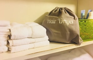 A shelf with neatly folded white towels and a drawstring bag labeled "Hair Dryer". - Cozy King by Red Rocks & Downtown Denver (Wheat Ridge)