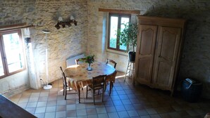 Un comedor rústico con pared de piedra, una mesa de madera con sillas, una planta en maceta y un aparador.