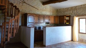 Una cocina con paredes de piedra, armarios de madera y suelo de baldosas.