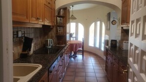 A kitchen with wooden cabinets, a granite countertop, and a dining area with a table and chairs. - "La Favorita: Mountain Serenity with Ocean Views". (Calpe)